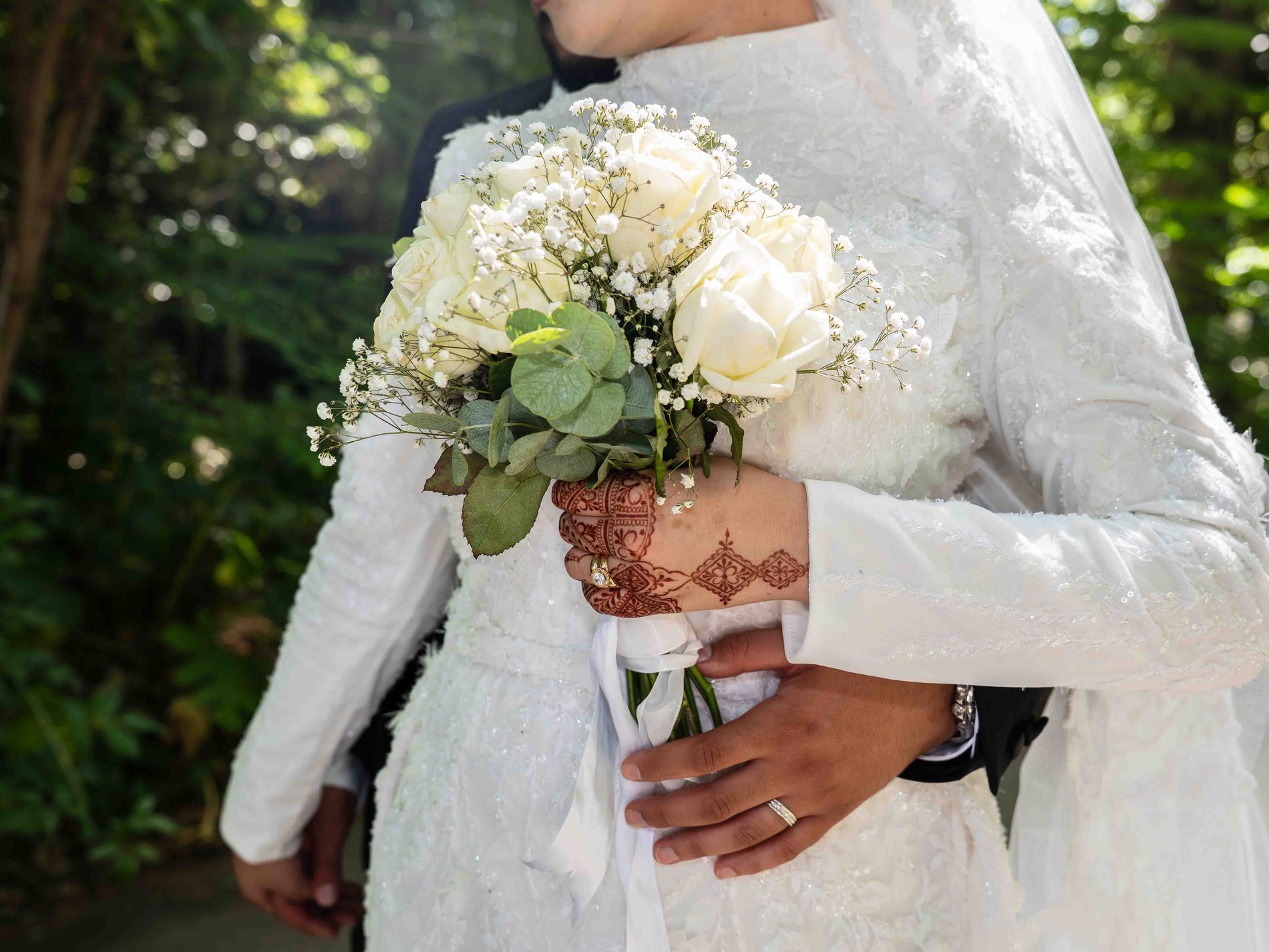 Bouquet de roses blanches tenu par la mariée, main ornée de henné