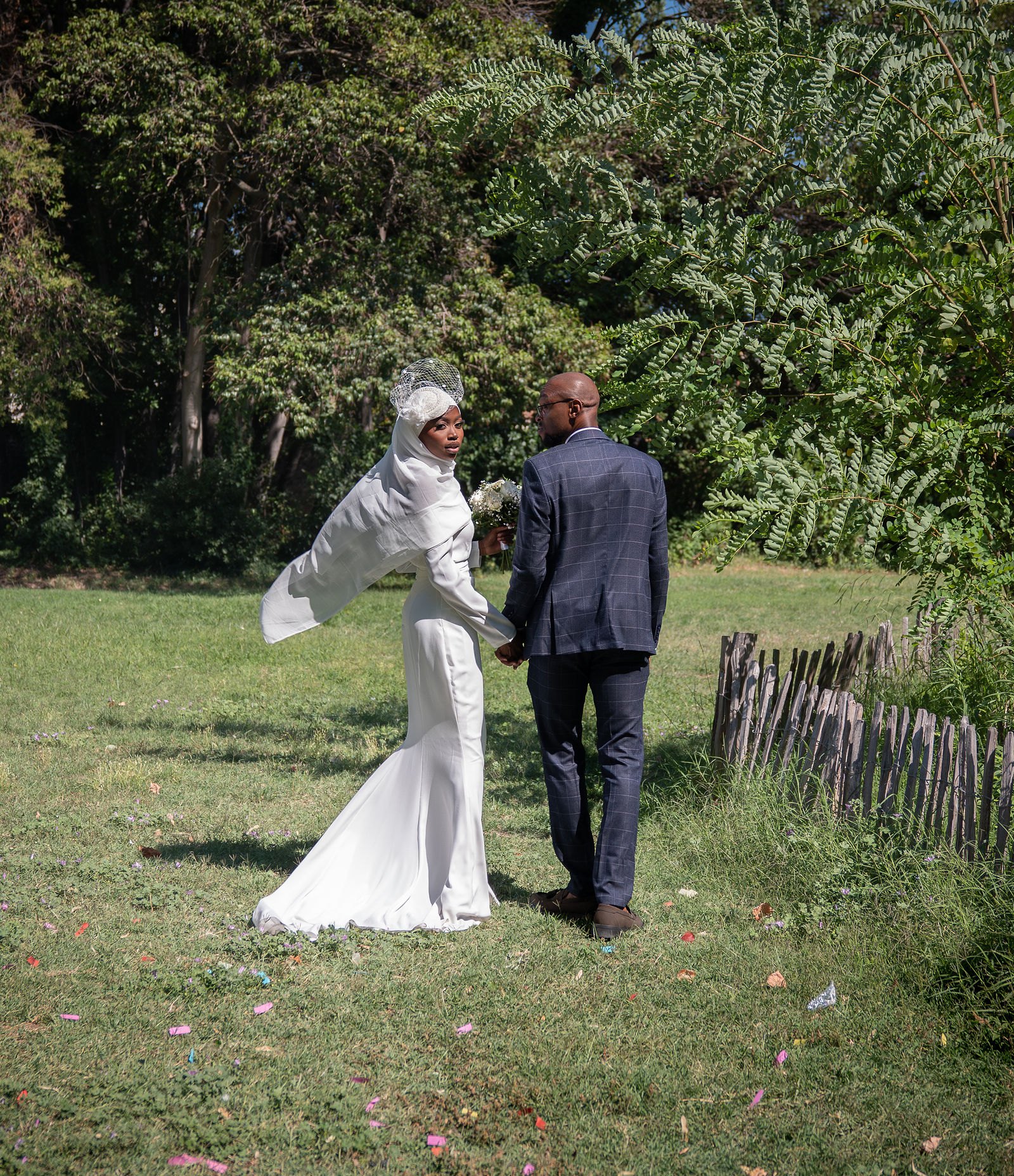 Les mariés s'éloignent dans l'herbe, voile porté par le vent
